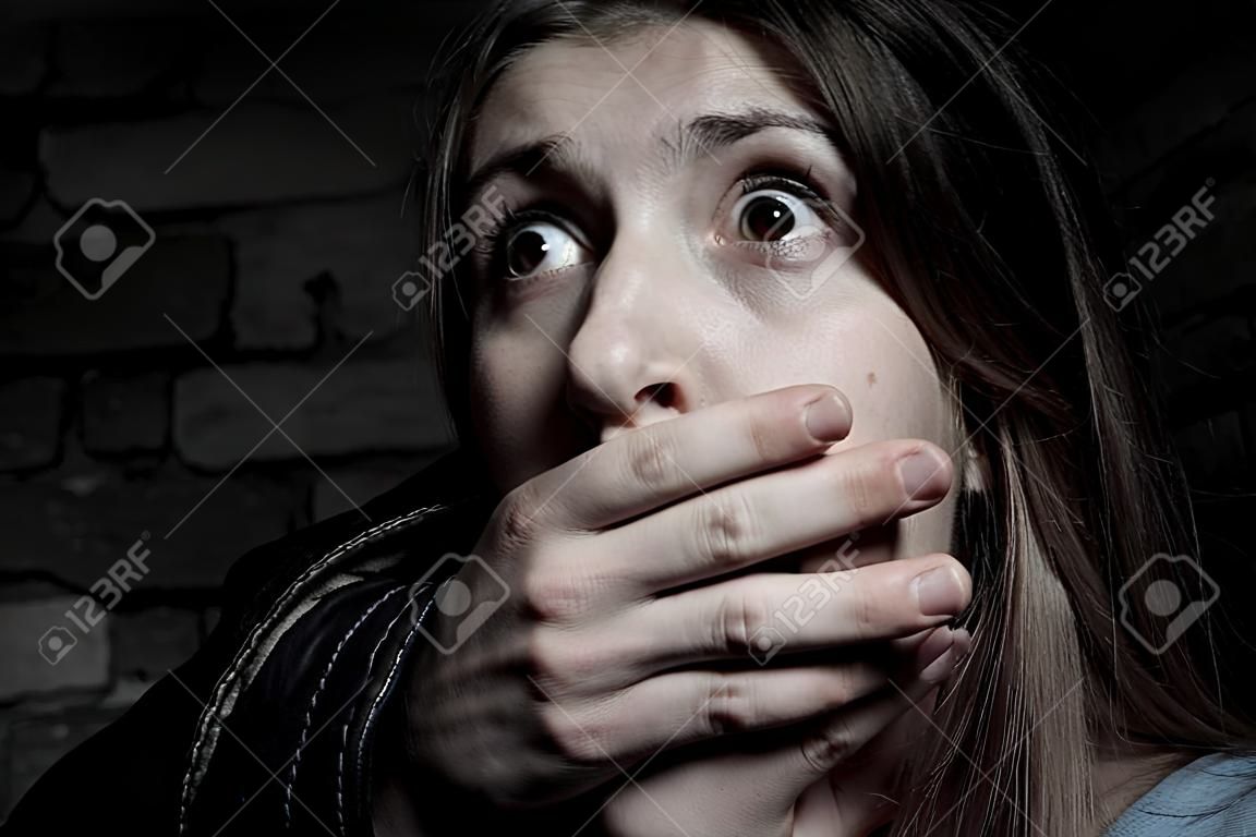 Entführung Verängstigt junge Frau mit der Hand über den Mund in die Kamera starrt