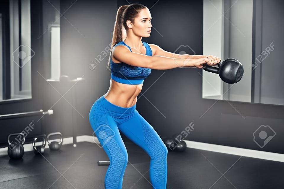 完美的交叉训练侧观完美的身体与运动水壶与水壶在健身房健身钟