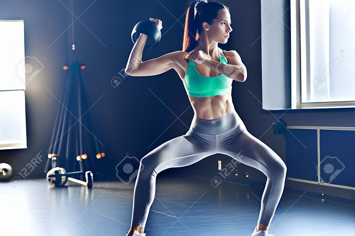 完美的交叉训练侧观完美的身体与运动水壶与水壶在健身房健身钟