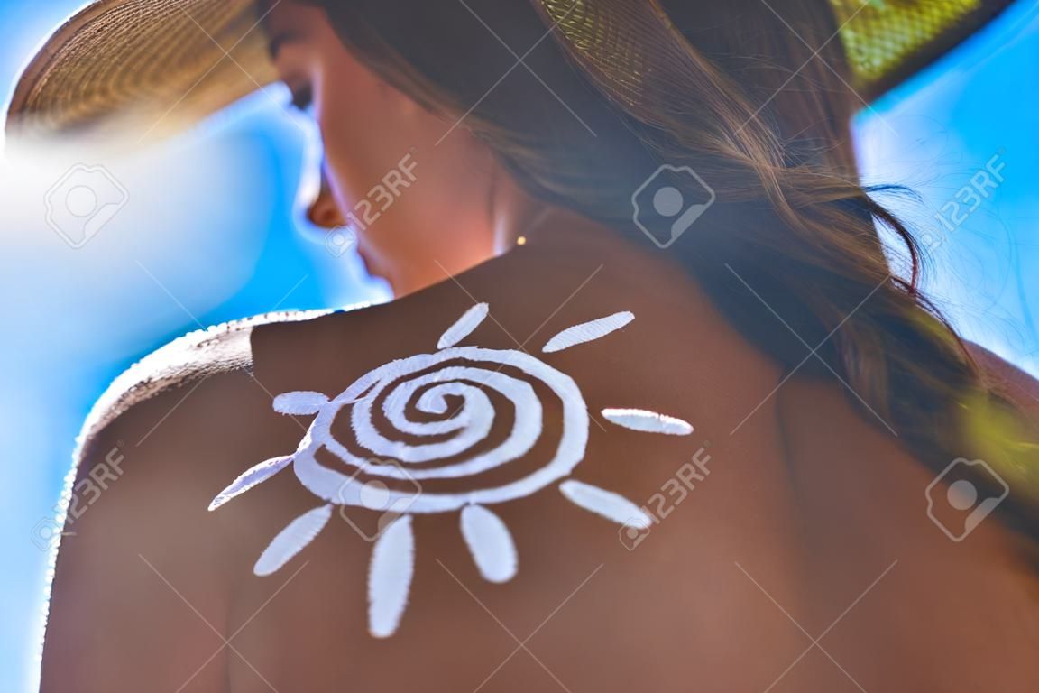 整個夏天保持安全。年輕女子的低角度後視圖，她坐在戶外曬日光浴的防曬霜