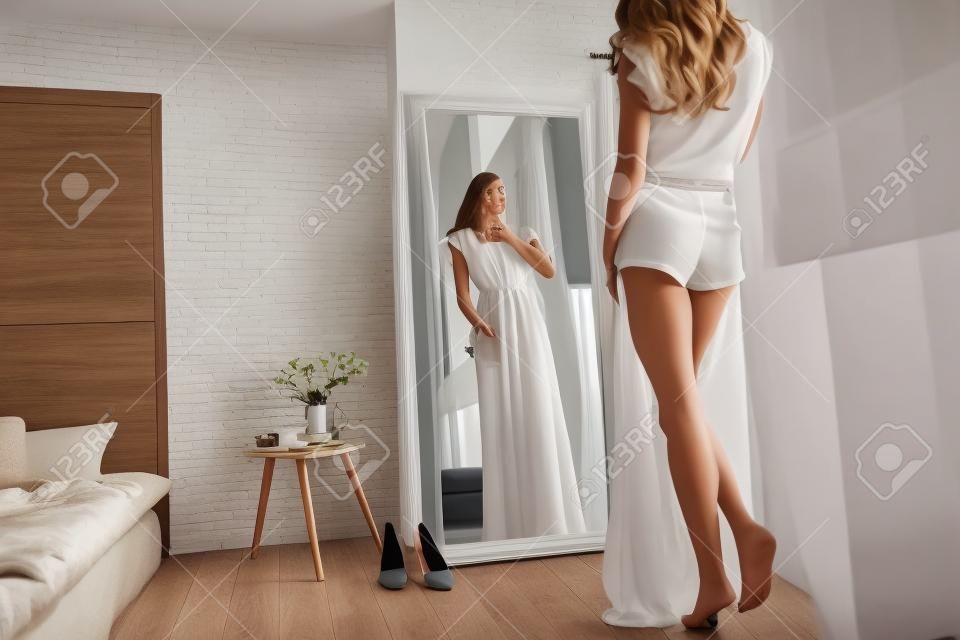 適合完美！有吸引力的年輕女子在家裡看鏡子時試穿她的衣服的後視圖