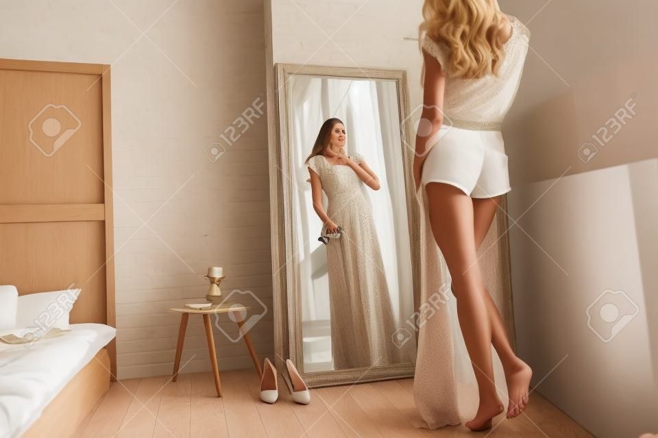 適合完美！有吸引力的年輕女子在家裡看鏡子時試穿她的衣服的後視圖