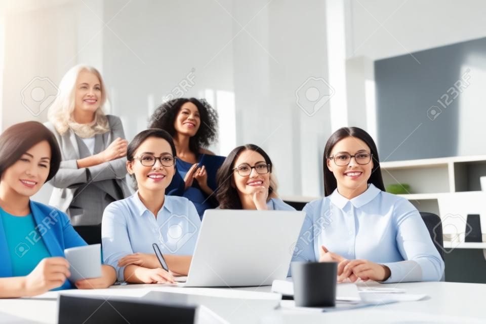 Group of mature women listening to speaker while having business training in the office