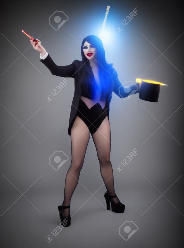 Güzel kadın sihirbaz hile yapıyor sihirli sopa ile kostüm takım elbise giymiş. Stüdyo çekimi