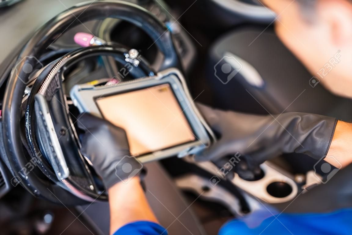 Diagnosi computerizzata dell'automobile. Il riparatore meccanico dell'auto cerca un guasto al motore sull'attrezzatura diagnostica nell'officina di assistenza del veicolo