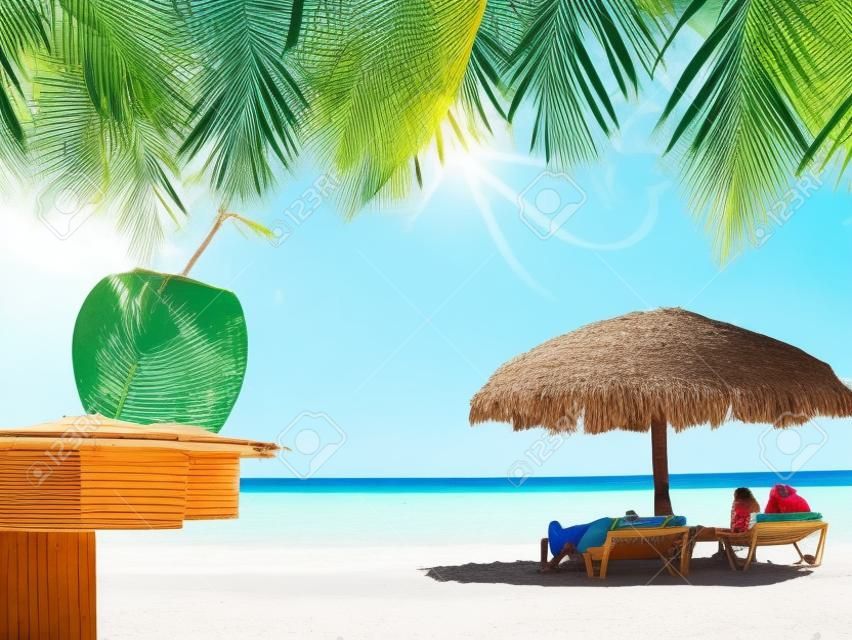 Люди отдыха в тропических хижин с кокосом и пальмовых листьев на переднем плане в кубинском пляже