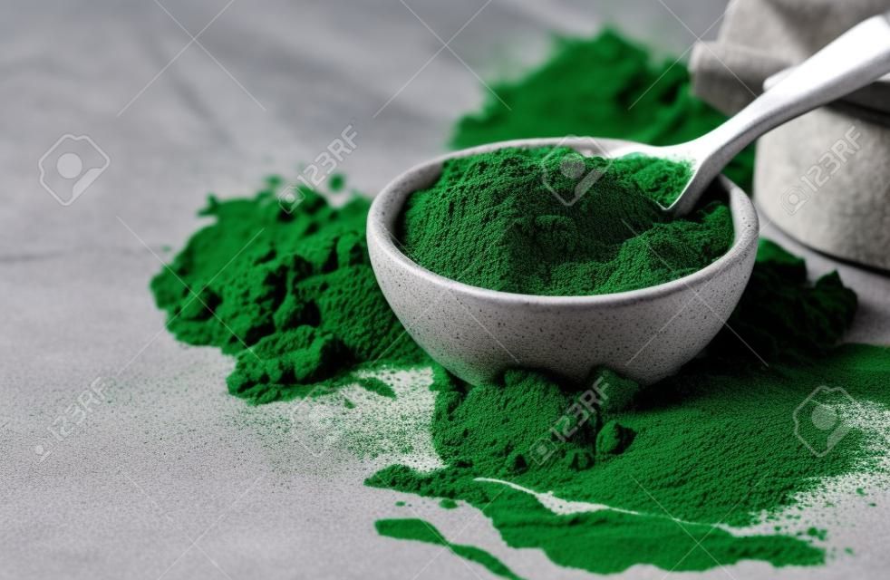 Grünes Pulver Chlorella, Spirulina auf grauem Betonhintergrund. Konzept Diät, Entgiftung, gesundes Superfood, das Protein enthält.