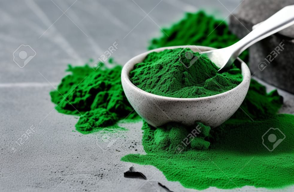 Clorella en polvo verde, espirulina sobre fondo de hormigón gris. Concepto de dieta, desintoxicación, superalimento saludable, que contiene proteínas.