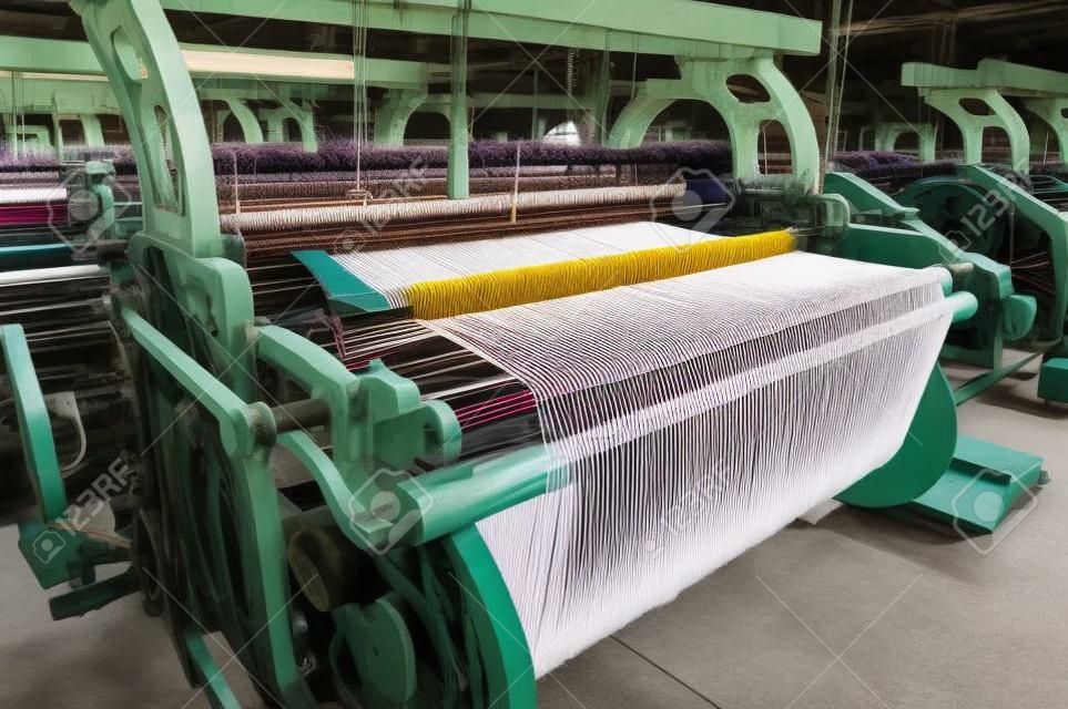 Una fila de los telares de tejer hilos de algodón en una fábrica textil.