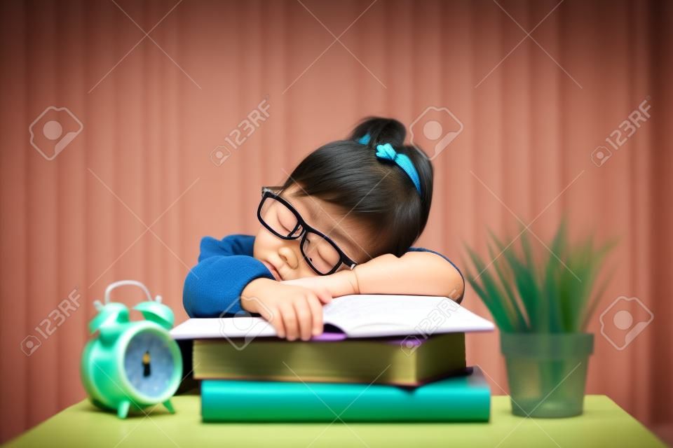 Cute little asian girl fall asleep while studying. Concept of education and tiredness