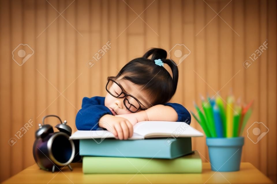 Cute little asian girl fall asleep while studying. Concept of education and tiredness