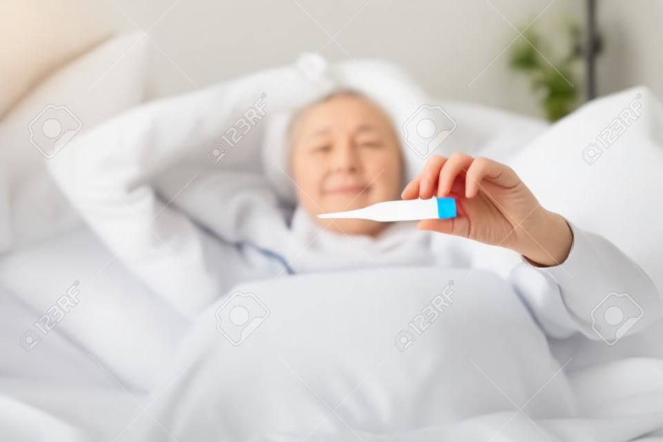 Beteg nő hőmérő ágyban fekve Ő nátha, az influenza és a magas láz