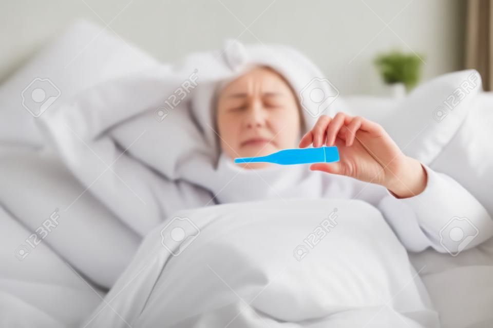 Beteg nő hőmérő ágyban fekve Ő nátha, az influenza és a magas láz