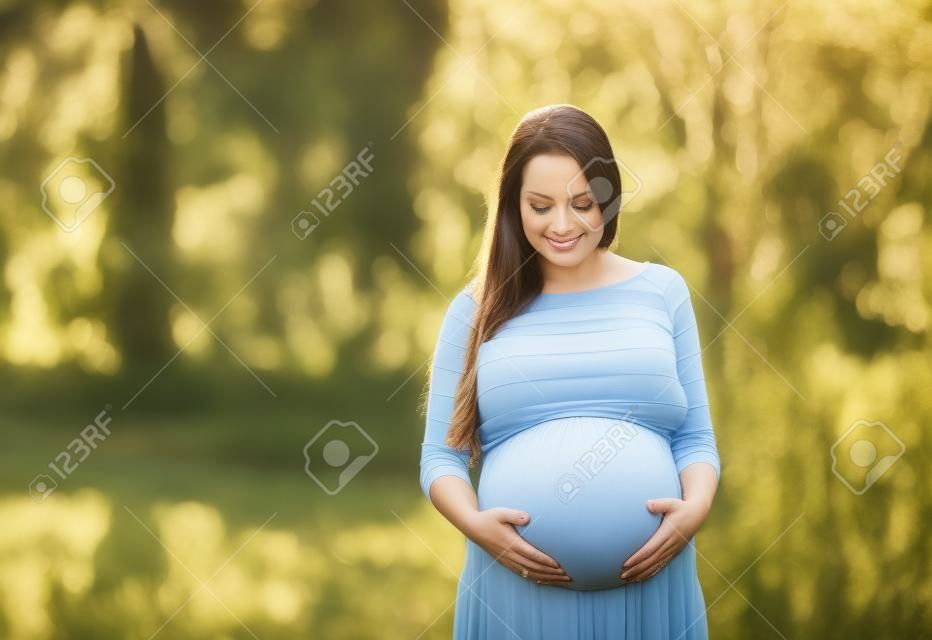 Outdoor Portrait der schönen schwangere Frau, die ihren Bauch