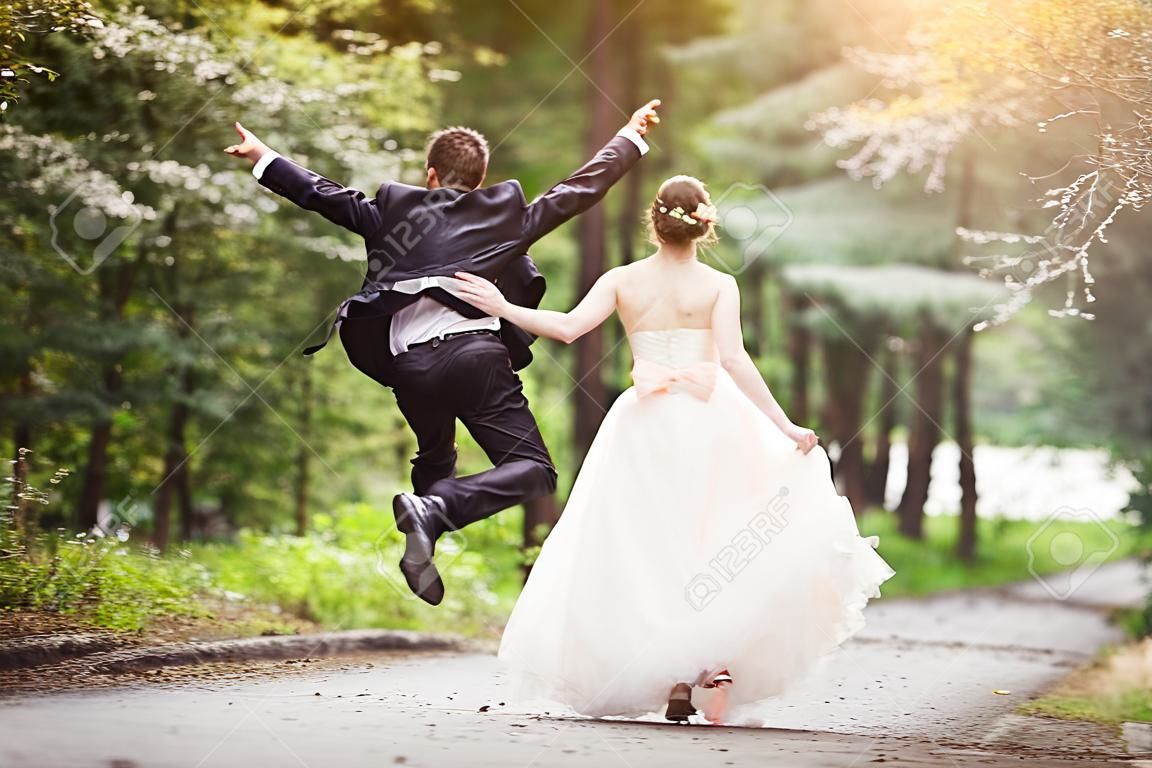 Casal de casamento - noiva e noivo - correndo pela estrada