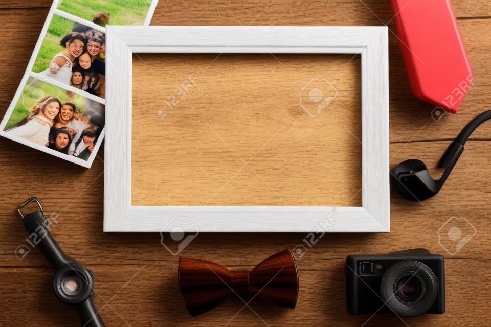 Picture frame, instant photos and various objects on wooden background.