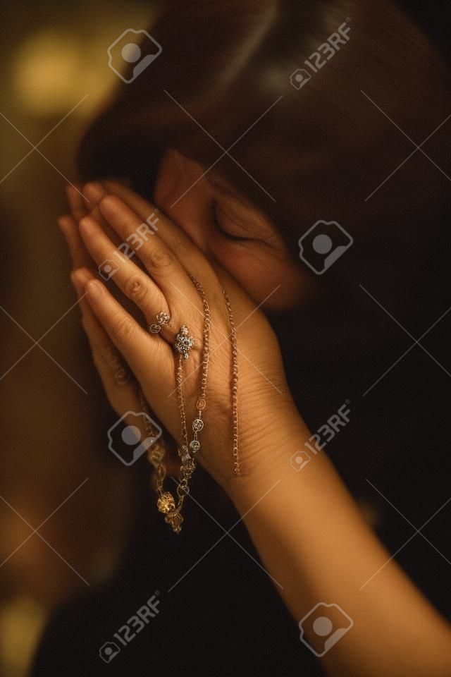 Unrecognizable woman with a rosary praying in the church