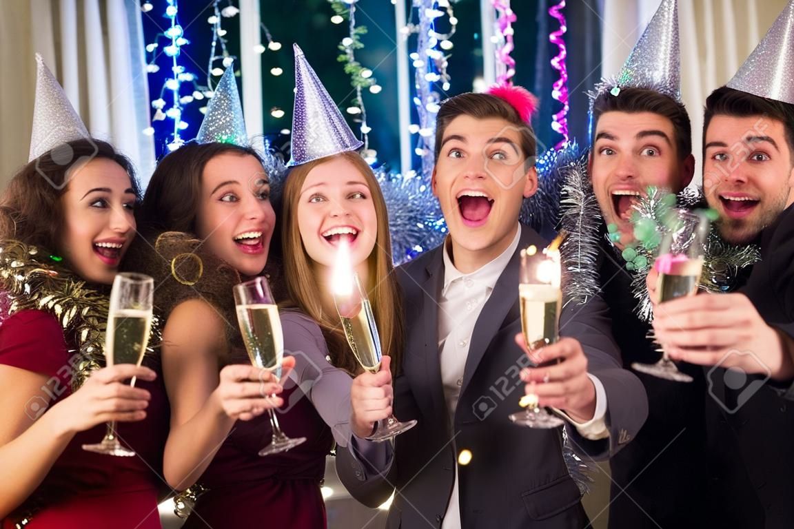 Grupa przyjaciół z okazji zakończenia roku, mając na imprezę w Sylwestra, trzymając kieliszki szampana.
