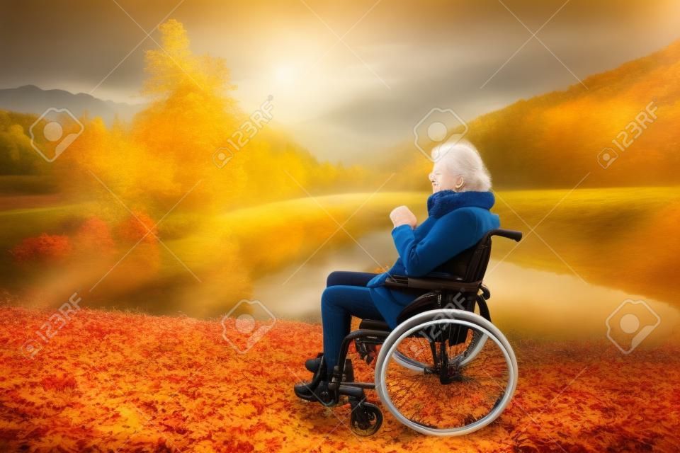 Старшая женщина в инвалидной коляске в осенней природе.
