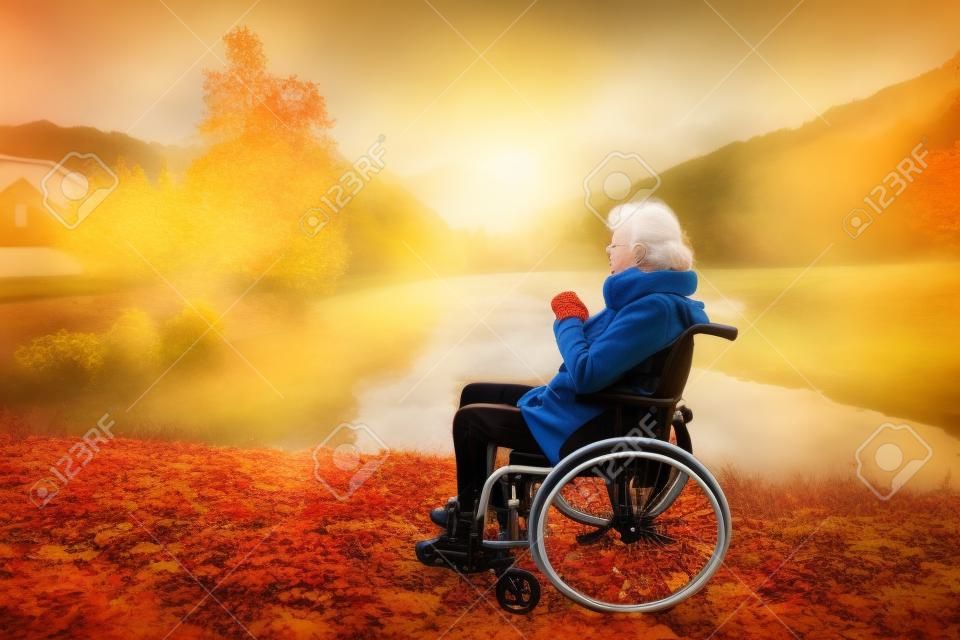 Ältere Frau in einem Rollstuhl in der Herbstnatur.