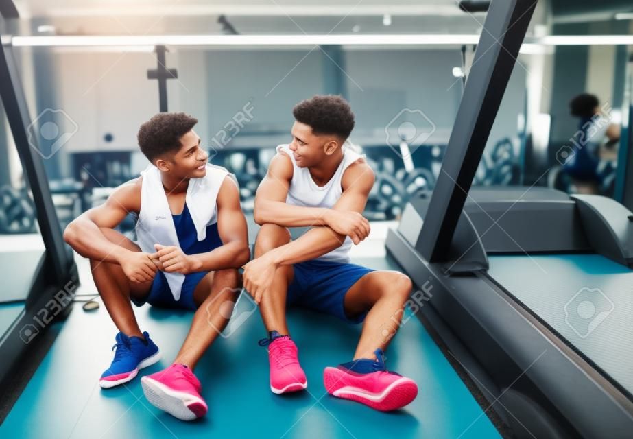 Young men in gym talking and resting after an exercise.