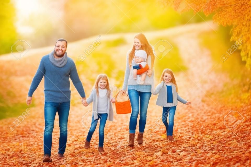 A young family with two small children walking in autumn nature.