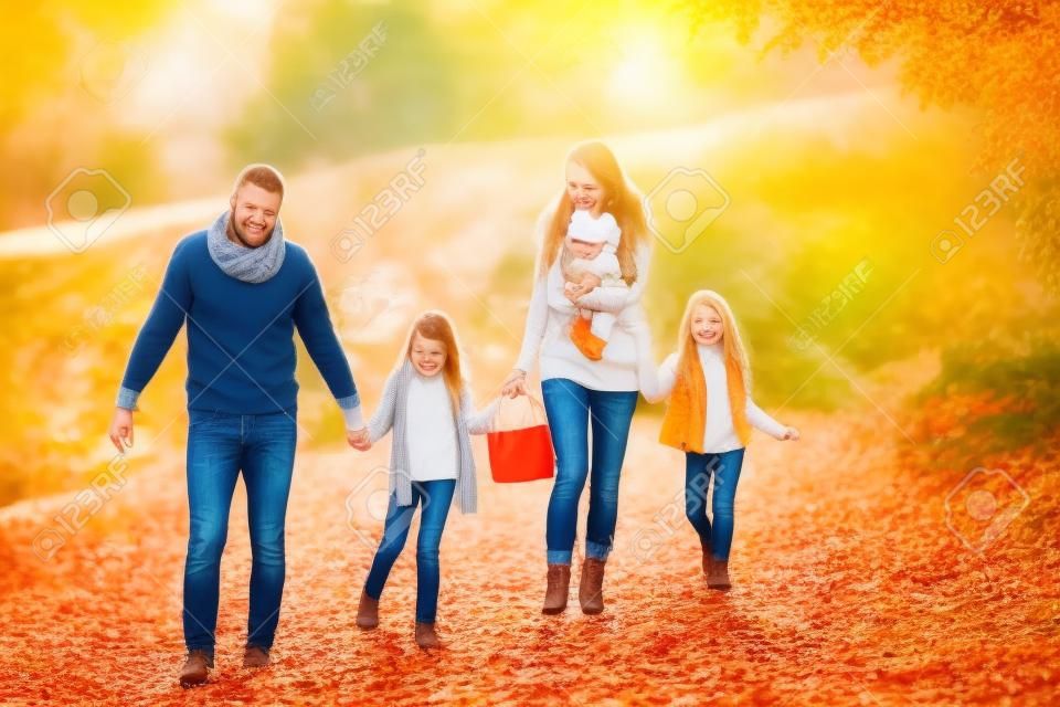 A young family with two small children walking in autumn nature.