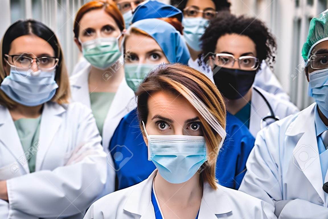 Groep van artsen met gezichtsmaskers kijken naar camera, corona virus concept.