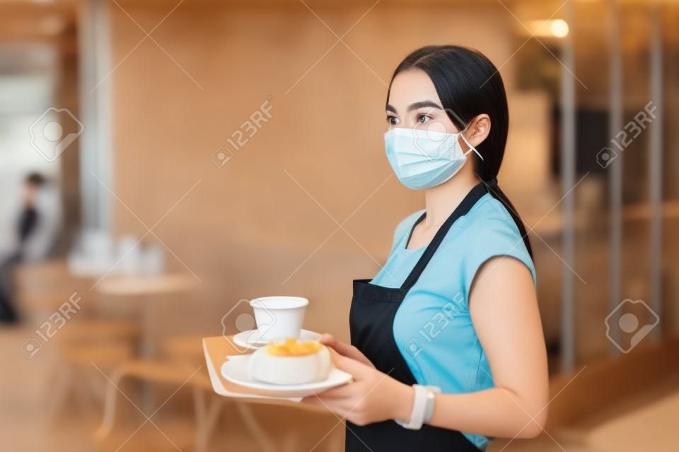 Jonge vrouw met gezichtsmasker werken in café, het bedienen van klanten.