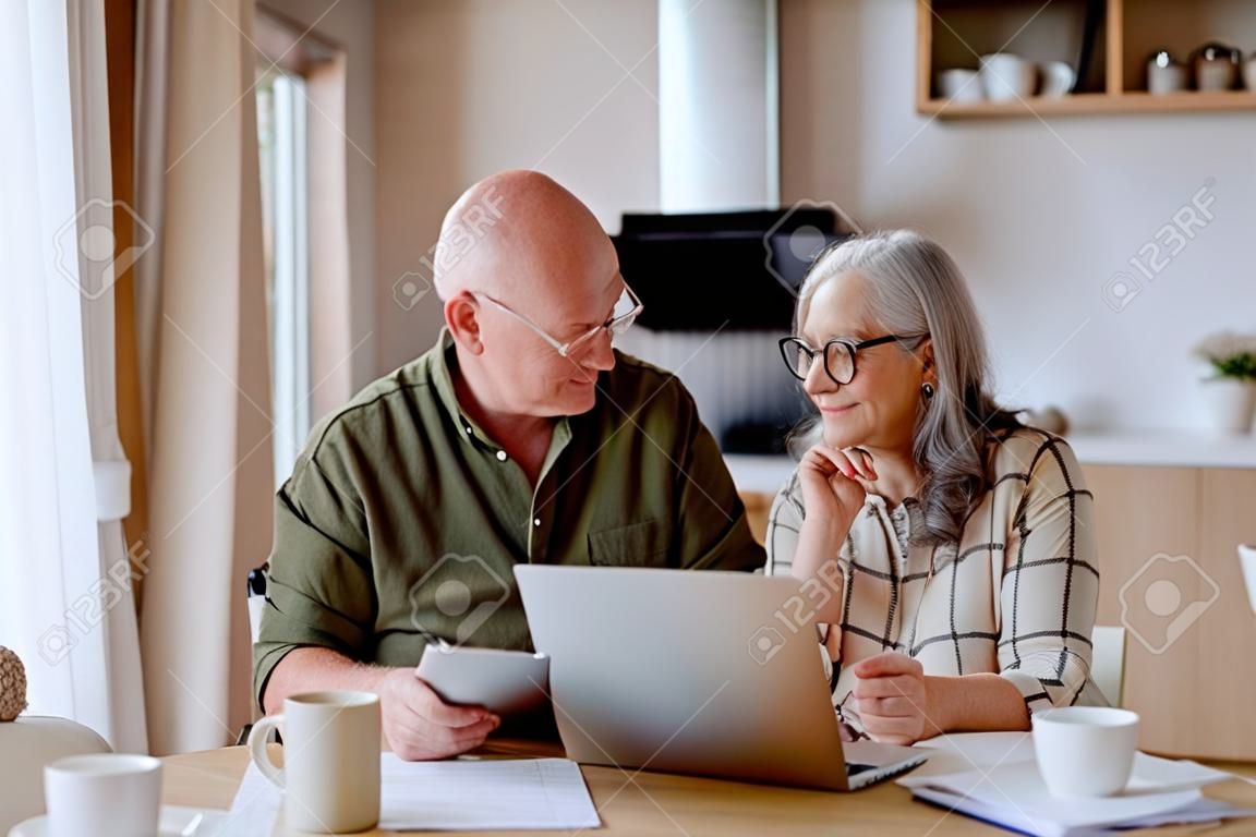 Un couple de personnes âgées heureux calcule les dépenses ou planifie le budget ensemble à la maison.