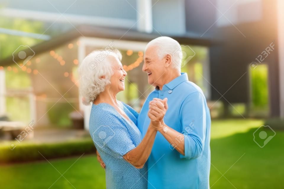 Starsza kobieta i mężczyzna tańczą razem w ogrodzie latem