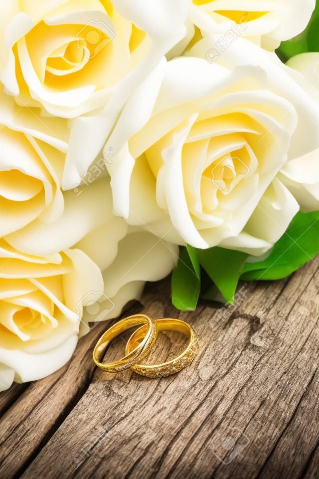 Hochzeits-Blumenstrauß und Goldringe auf altem Holz