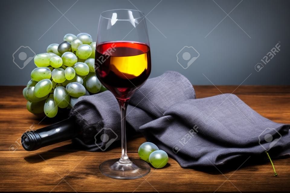 Bottiglie di vino, grappolo d'uva e bicchiere di vino bianco su vecchio fondo di legno blu