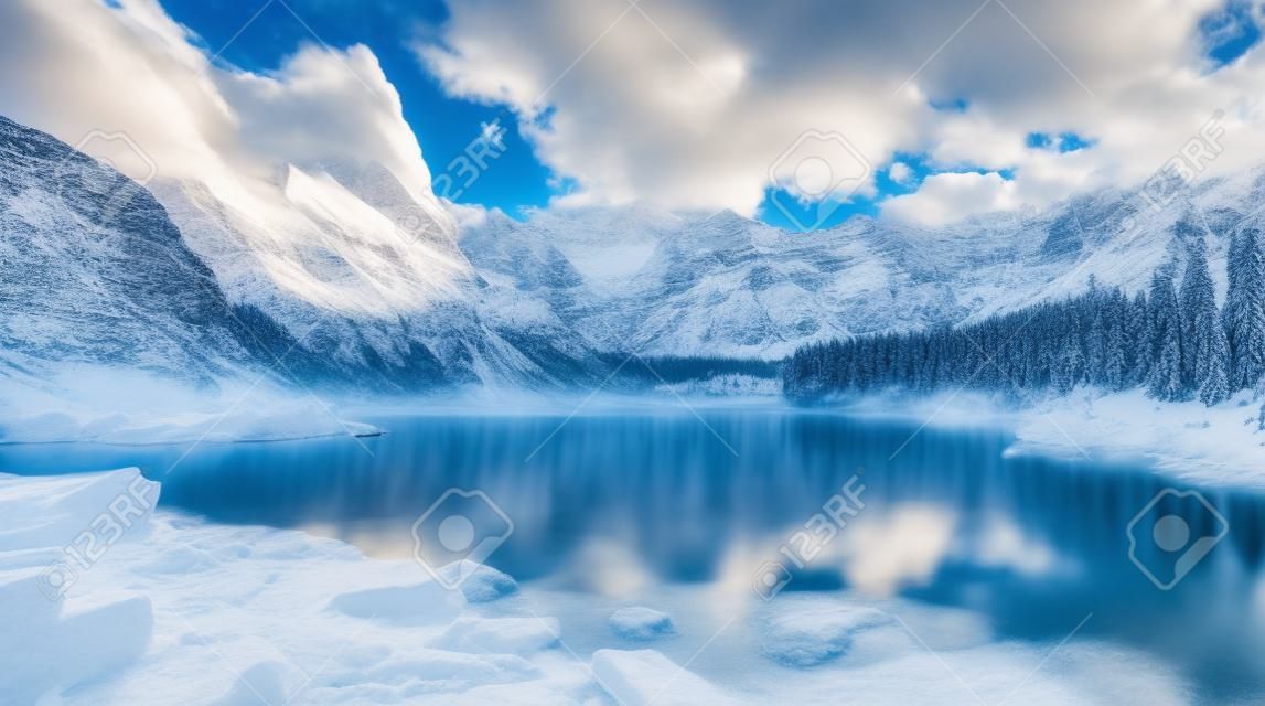 Panoramic view of snowy mountains and clear blue lake.