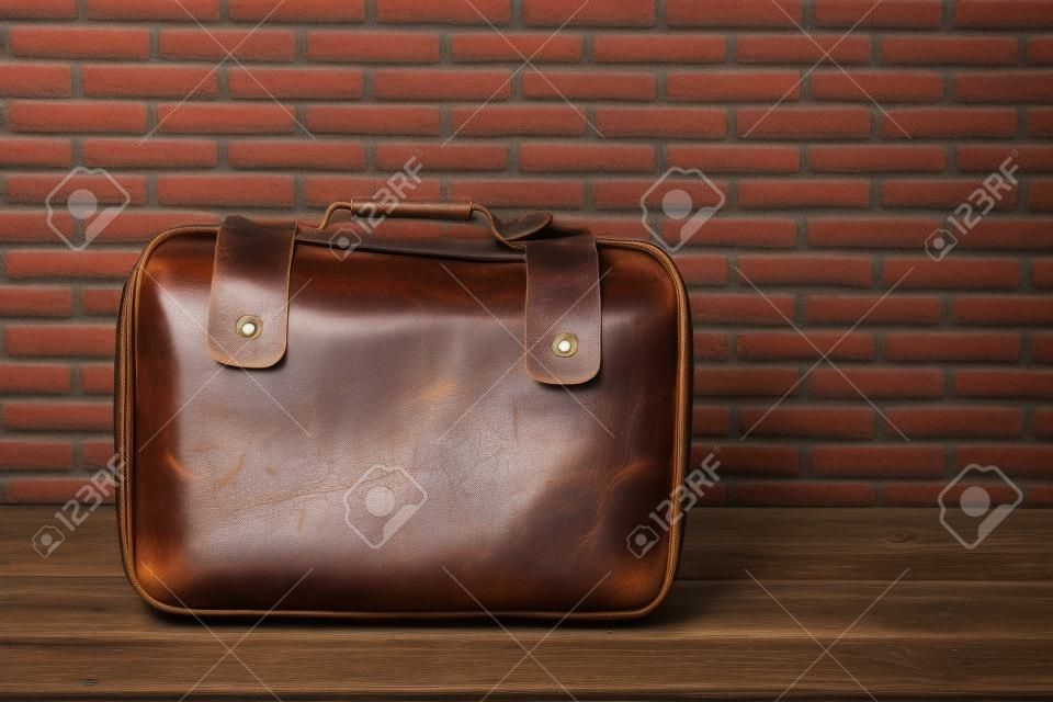 Vecchio stile di borsa per bagagli in pelle vintage con sfondo muro di mattoni
