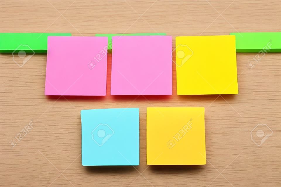 Five colorful sticky notes on wooden board 