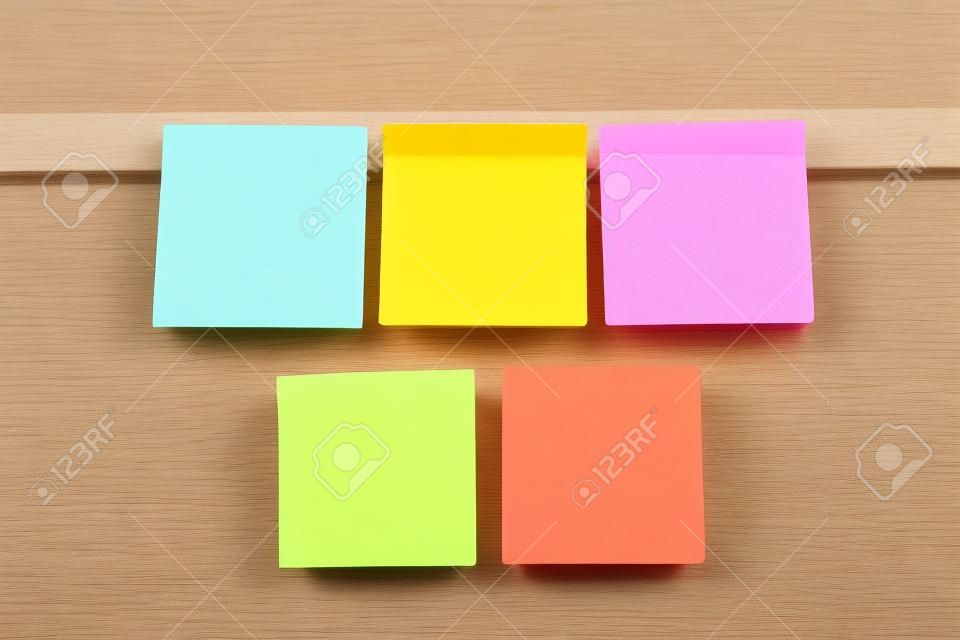 Five colorful sticky notes on wooden board 
