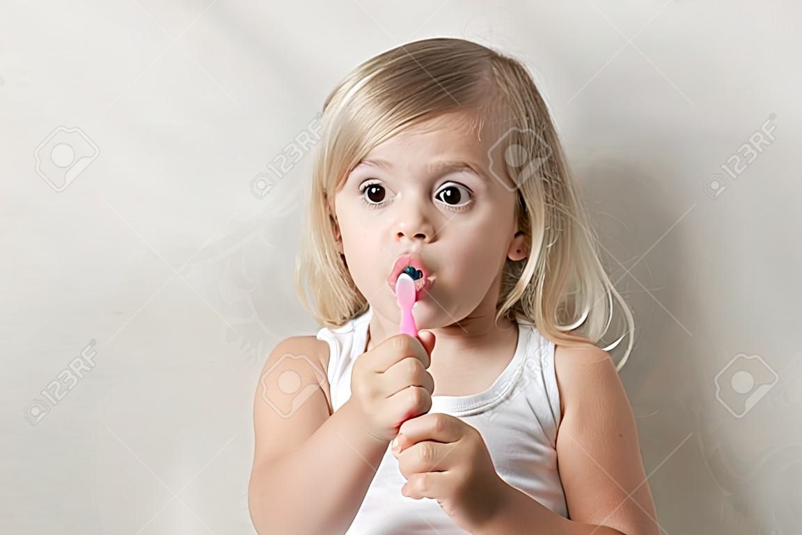 Kleine meisje brushes tanden met tandenborstel. Tandheelkunde gezondheid. In isolatie