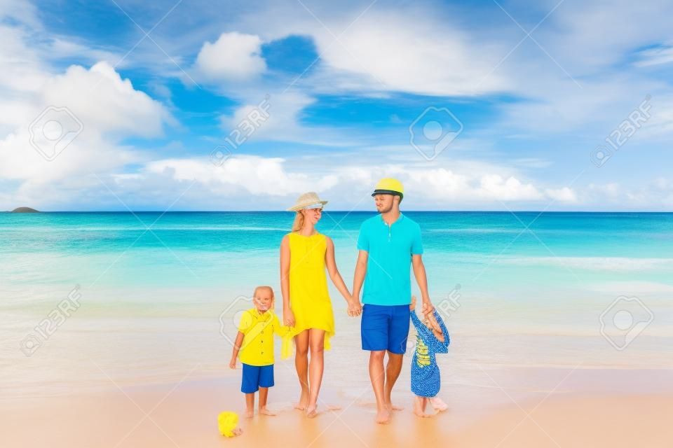 Familie am wunderschönen Strand Petite Anse, junges Paar in Gelb mit dreijährigem Kleinkind. Sommerurlaub auf den Seychellen, Mahe.