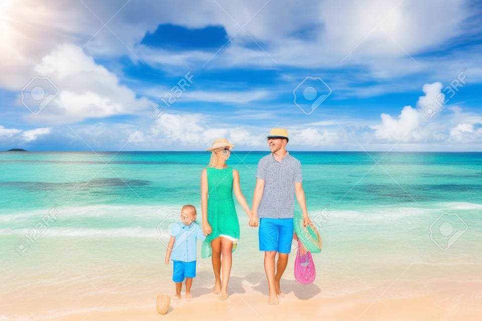 Familie am wunderschönen Strand Petite Anse, junges Paar in Gelb mit dreijährigem Kleinkind. Sommerurlaub auf den Seychellen, Mahe.