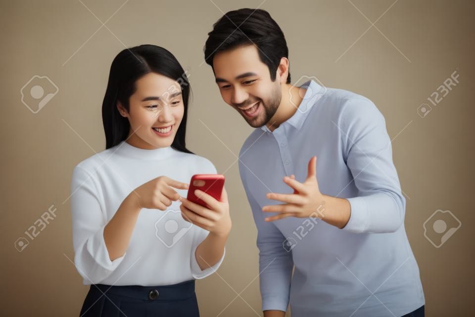 Portrait of young couple using phone on background