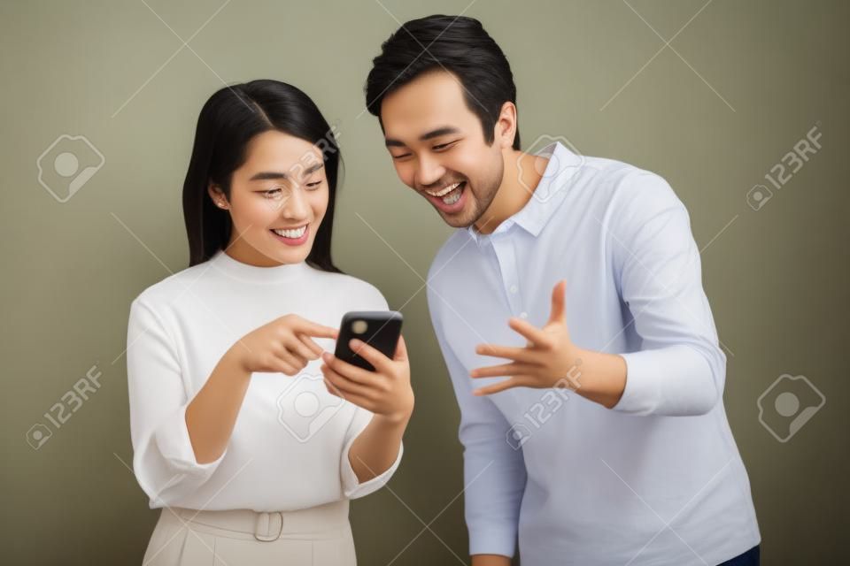 Portrait of young couple using phone on background