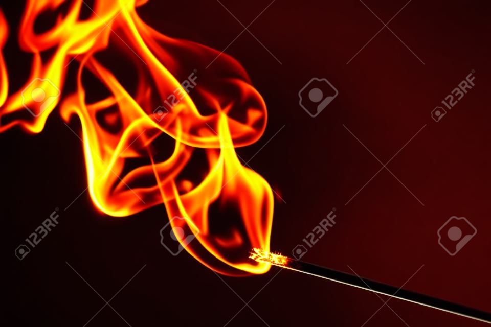 flame and smoke of a matchstick on black background