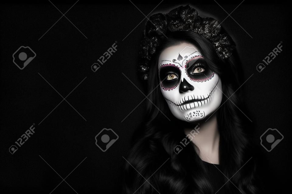 Retrato de una mujer con maquillaje de calaveras de azúcar sobre fondo negro. Disfraz y maquillaje de Halloween. Retrato en blanco y negro de Calavera Catrina