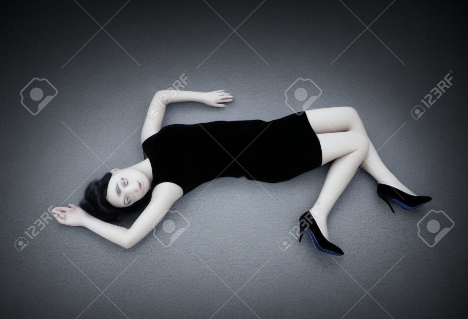 Piękna martwa kobieta w czarnej sukni leżącej na podłodze.