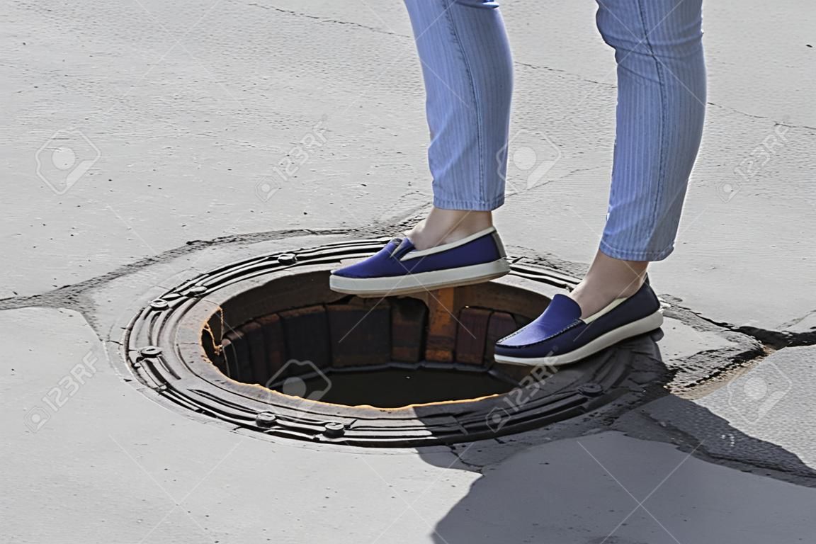 The girl steps into the open sewer hatch, sewer hatch without lid