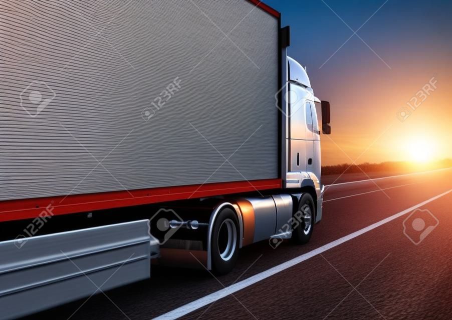 a truck with an isotherm semitrailer transports cargo along the highway against the backdrop of an evening sunset. Concept of delivery of goods, cargo transportation