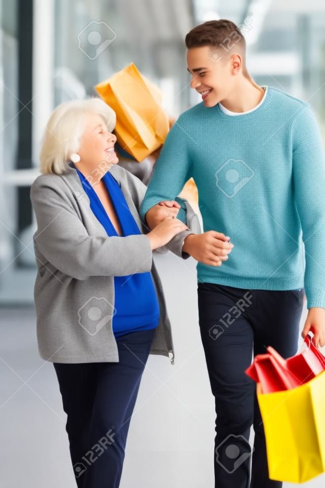 十几岁的男孩帮助高级妇女携带购物