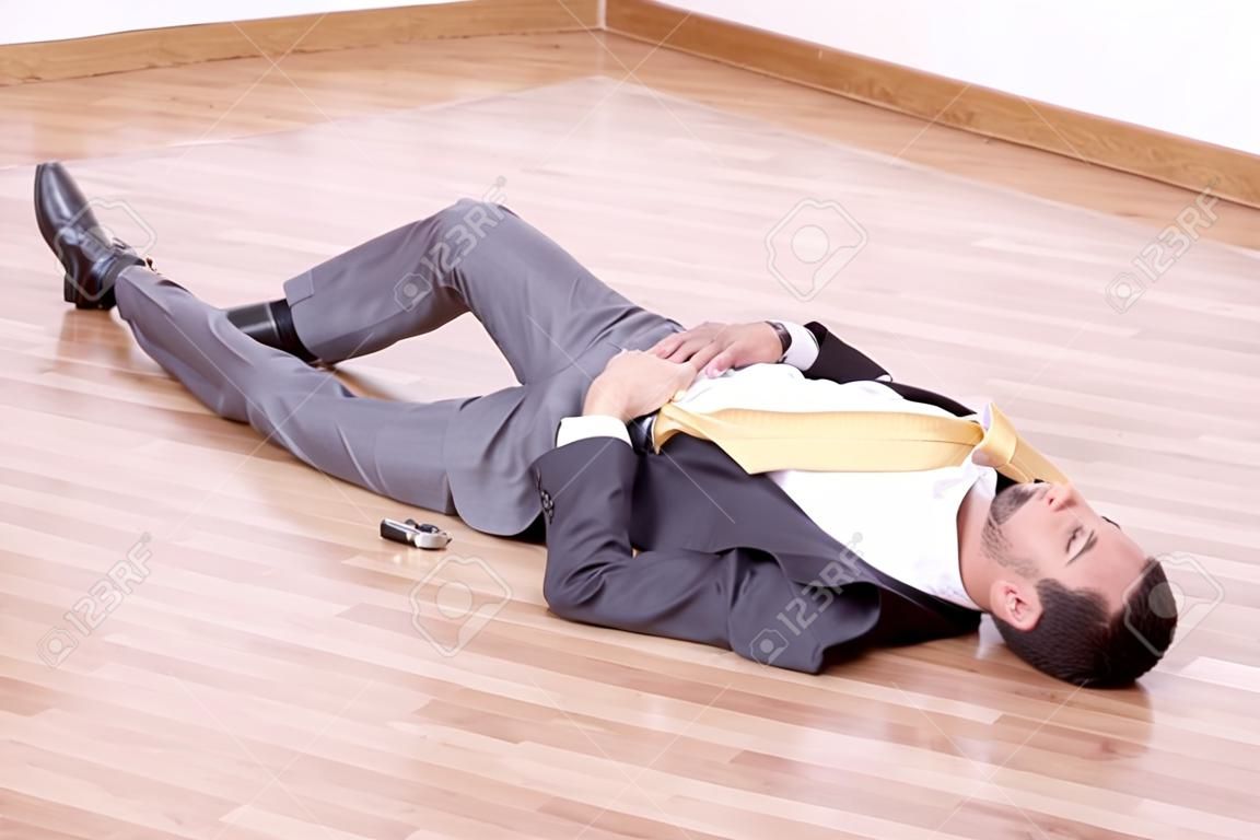 Businessman lying dead in the office floor with a gun in his hand
