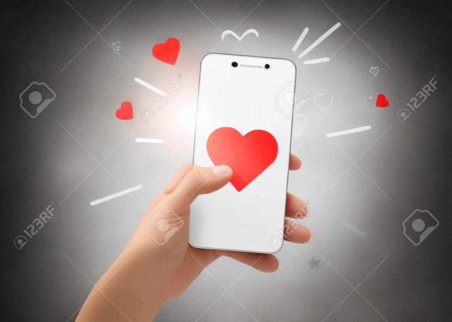 Hand holding phone with heart symbol. Social networking concept.